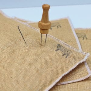 Hessian needle felting mats that can be filled with rice. There is a felting needle stuck in the top of the mat.