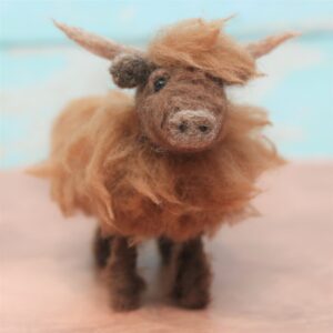 Image shows a cute needle felted Highland cow. Background is a sky blue.