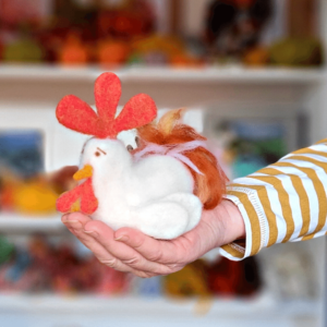 image shows a needle felted chicken in the palm of the hand