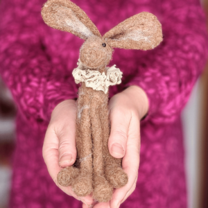 Image shows a brown needle felted hare being held in cupped hands. It has a lace ruffle collar and big ears