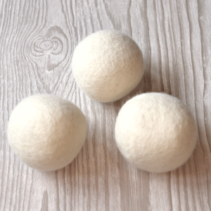 Image shows three wool dryer balls on a wooden table