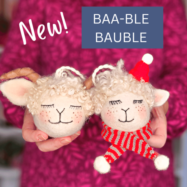 Image shows two cute needle felted sheep baubles with a hat, scarf and horns.