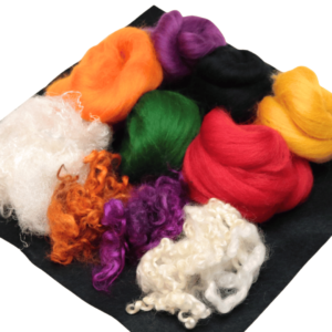 Assortment of halloween needle felting wool colours and black craft felt on a white background.