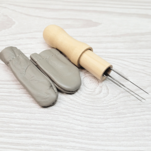 Leather finger protectors for needle felting, and a felting needle multi tool. Backgound is a light wood effect.